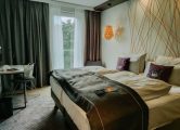A modern and cozy hotel room featuring a double bed, stylish lighting, and a workspace.