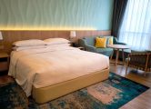 Spacious hotel room featuring a comfy bed, stylish furniture, and elegant lighting for a luxurious stay.